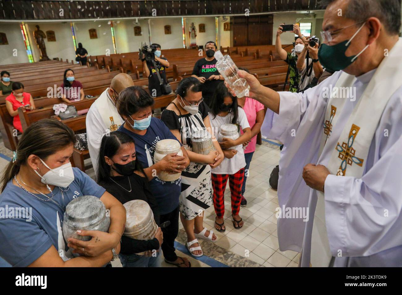 Manila, Filippine. 28th Set, 2022. Un sacerdote spruzza acqua Santa sui familiari e sui parenti delle vittime della guerra alla droga durante un servizio commemorativo all'interno di una chiesa cattolica a Quezon City, Metro Manila, Filippine. Settembre 28, 2022. I resti sono stati esumati dalle loro tombe dopo il leasing sulle tombe in un cimitero pubblico sono stati sepolti scaduti e i parenti non potevano permettersi di continuare con esso. (Credit Image: © Basilio Sepe/ZUMA Press Wire) Foto Stock