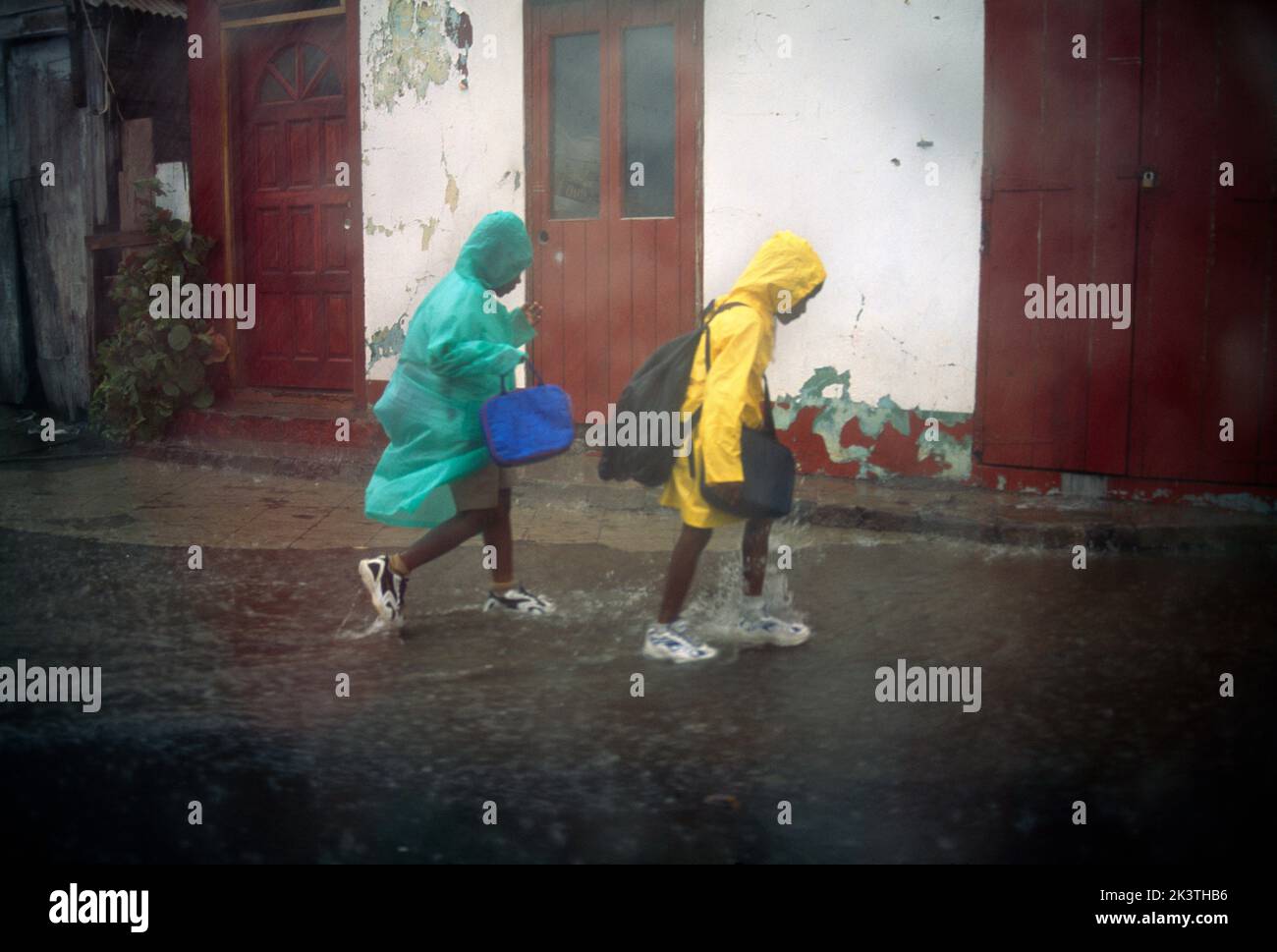 Basseterre St Kitts Bambini che corrono attraverso la pioggia durante la tempesta tropicale Foto Stock