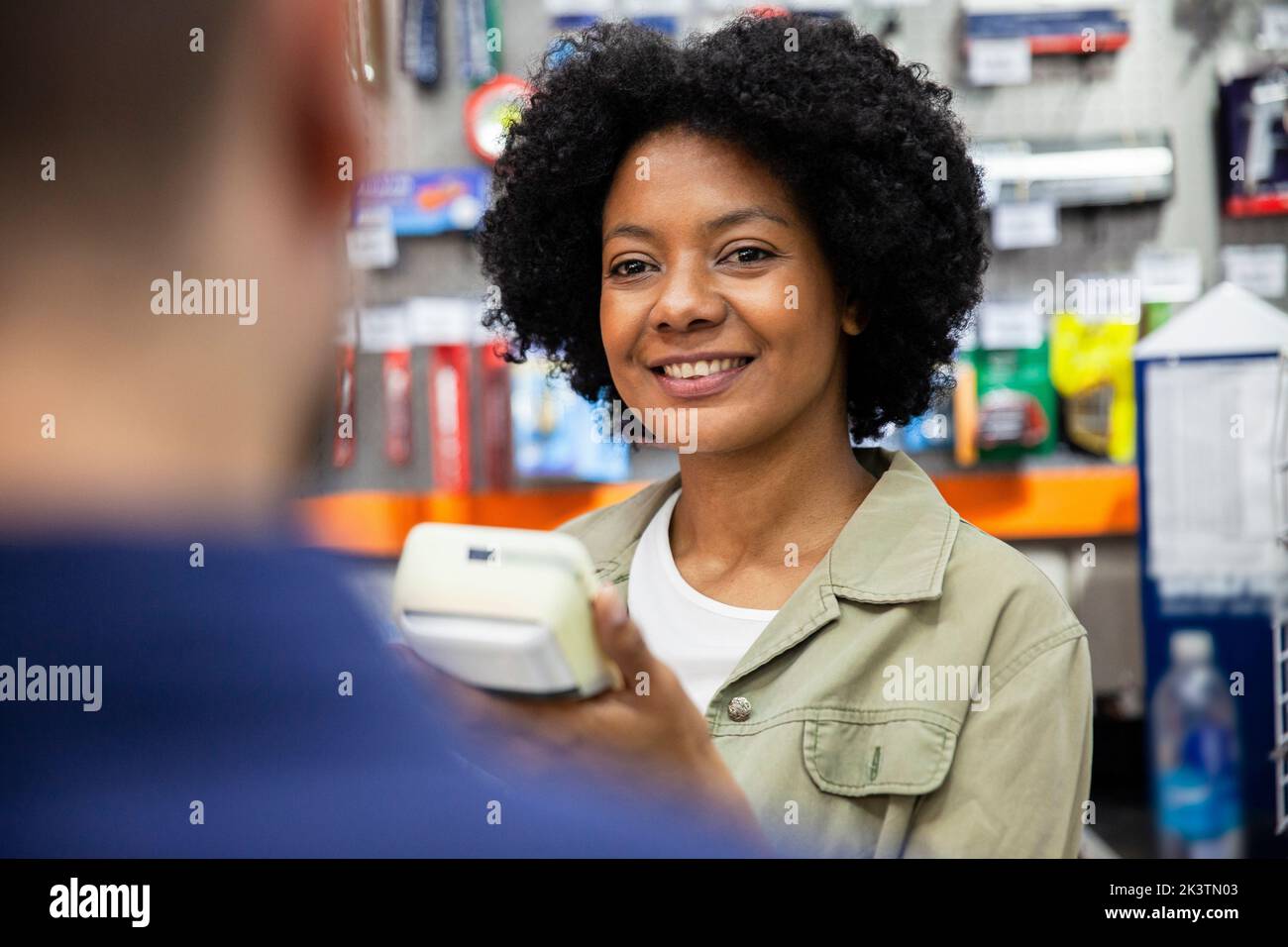 Donna afro-americana di ferramenta che assiste il cliente al negozio Foto Stock