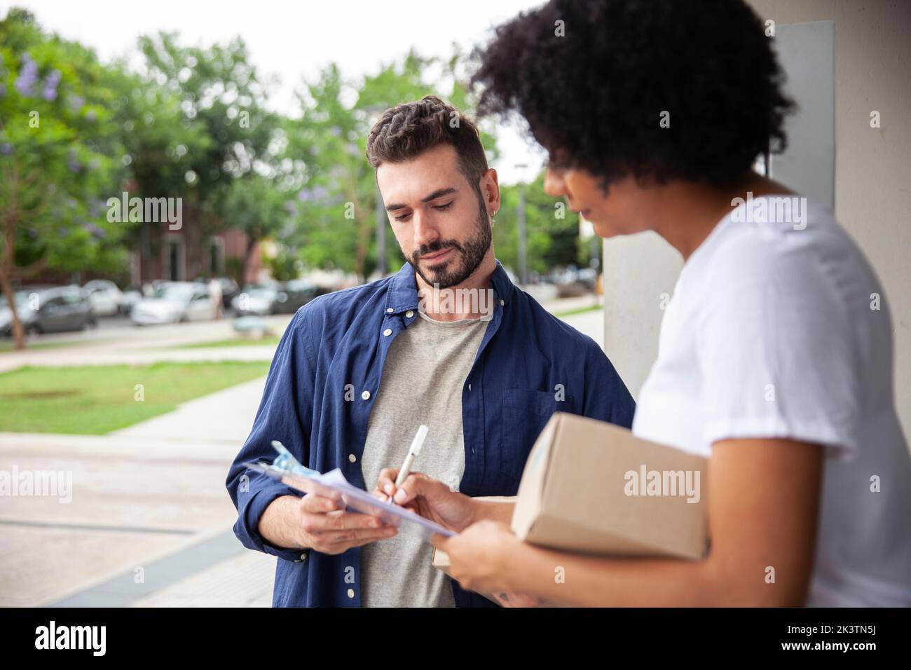 Addetto alla consegna che tiene gli appunti mentre il cliente lo firma Foto Stock