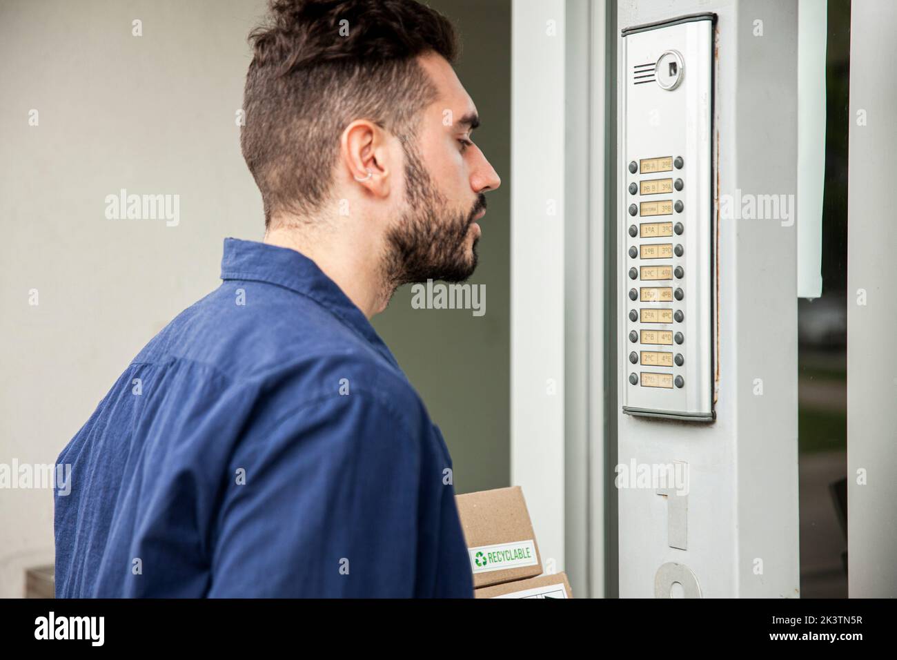 Addetto alla consegna in piedi sulla porta mentre aspetta di essere assistito Foto Stock