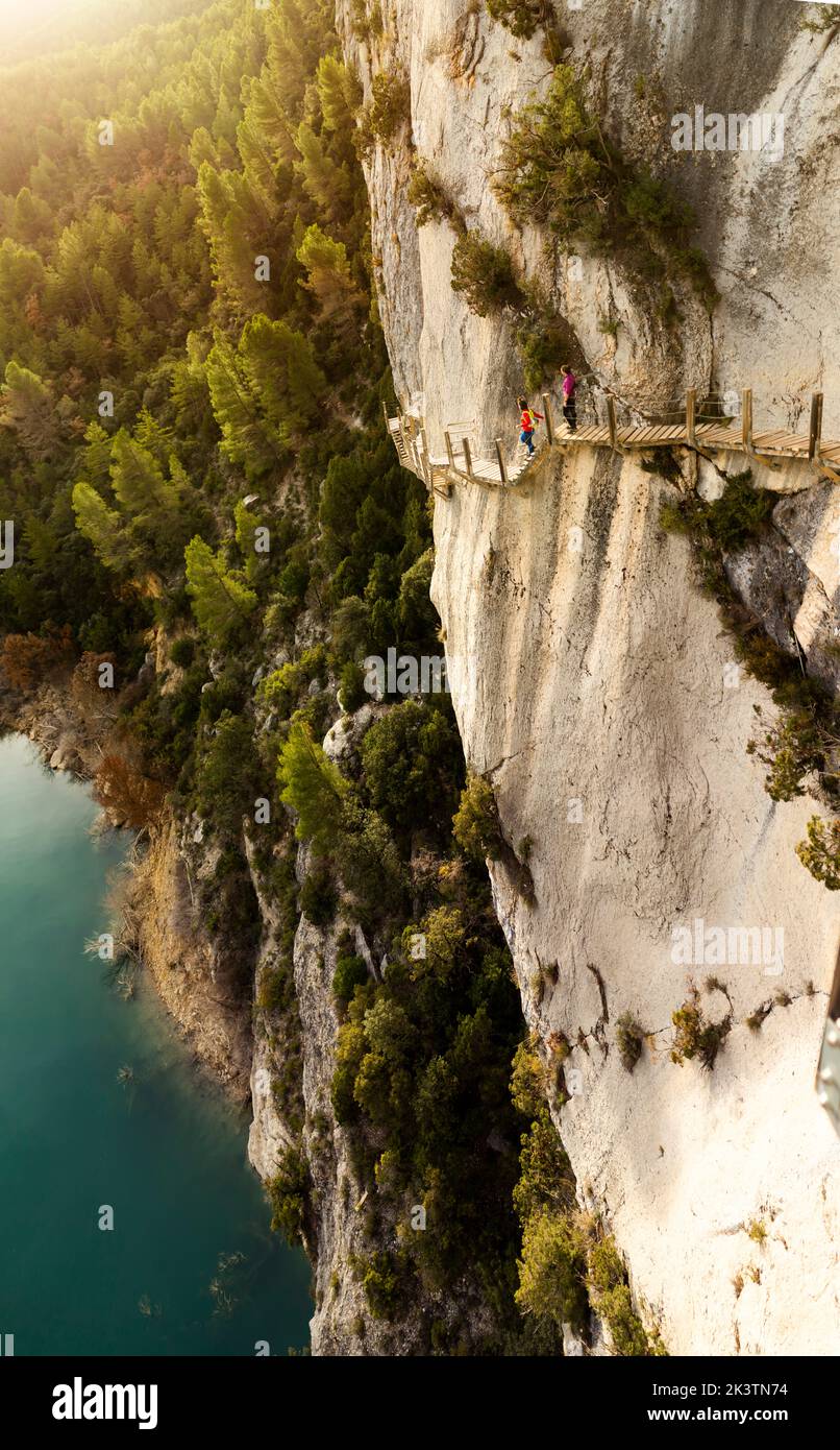 I viaggiatori che camminano sul sentiero del legname sulla scogliera nel Canyon del Mont Rebei il giorno d'estate nei Pirenei Foto Stock