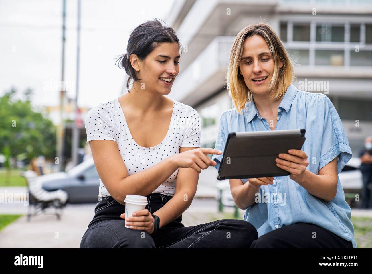 Immagine frontale di due nomadi digitali femminili che lavorano all'aperto Foto Stock