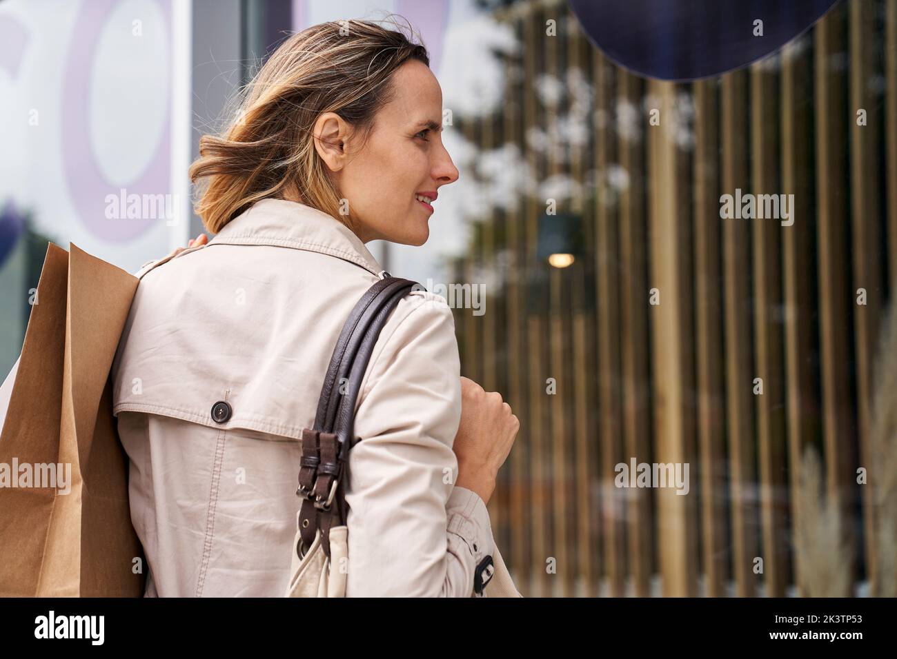 Vista laterale ripresa di una donna che trasporta borse durante lo shopping in vetrina Foto Stock