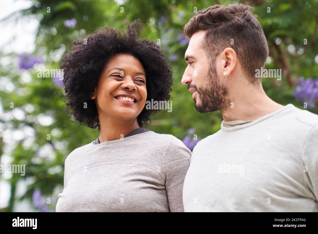 Ritratto a metà strada di una donna afro-americana e di un uomo caucasico sorridenti l'uno all'altro e che si divertono all'aperto Foto Stock