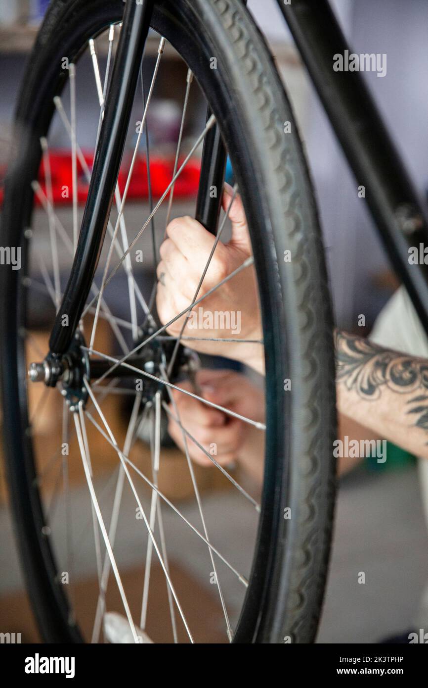 Primo piano di un giovane adulto uomo reparigin bicicletta ruota Foto Stock
