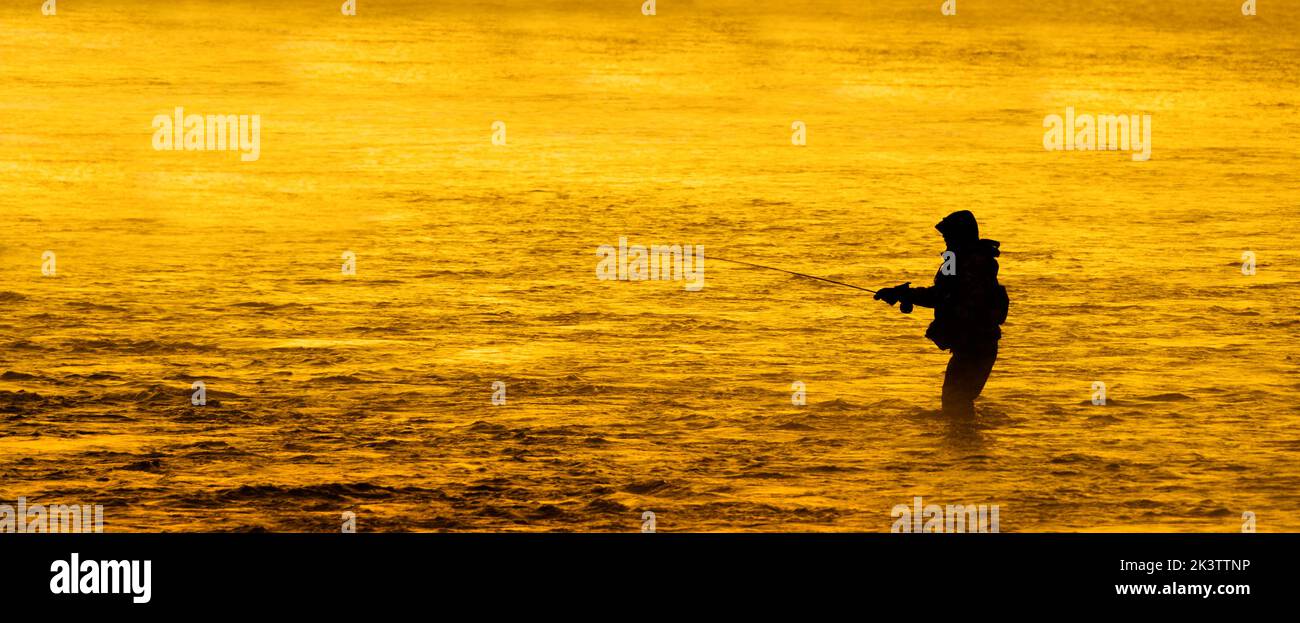 Silhouette della pesca a mosca rod reel in fiume con la luce del sole dorato Foto Stock