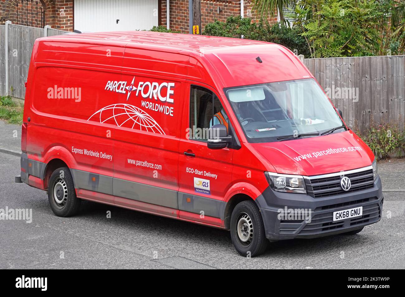 Parcelforce Worldwide Courier & Logistics service un nome commerciale di Royal Mail Postal Service rosso VW furgone e conducente consegna pacchi nel villaggio del Regno Unito Foto Stock