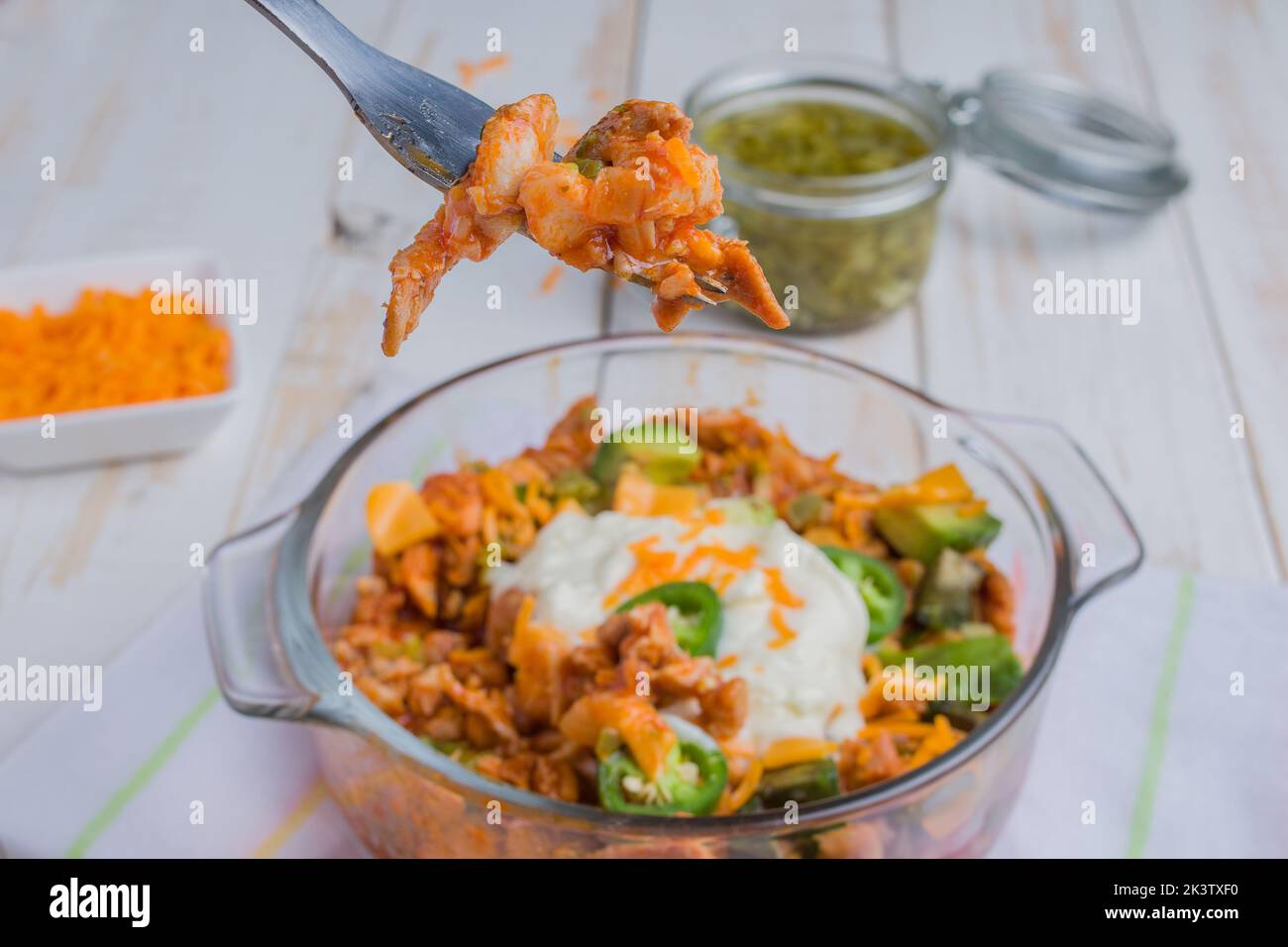 Dall'alto di una ciotola di vetro con gustosa insalata di enchilada di pollo servita con peperoni jalapeno verdi posti su un tavolo di legno Foto Stock