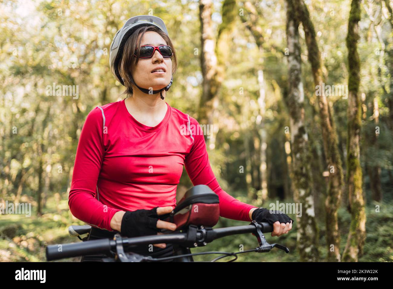 Sport in casco e occhiali da bicicletta guardando avanti mentre contempla la natura dalla bicicletta durante il giro di fondo nei boschi Foto Stock
