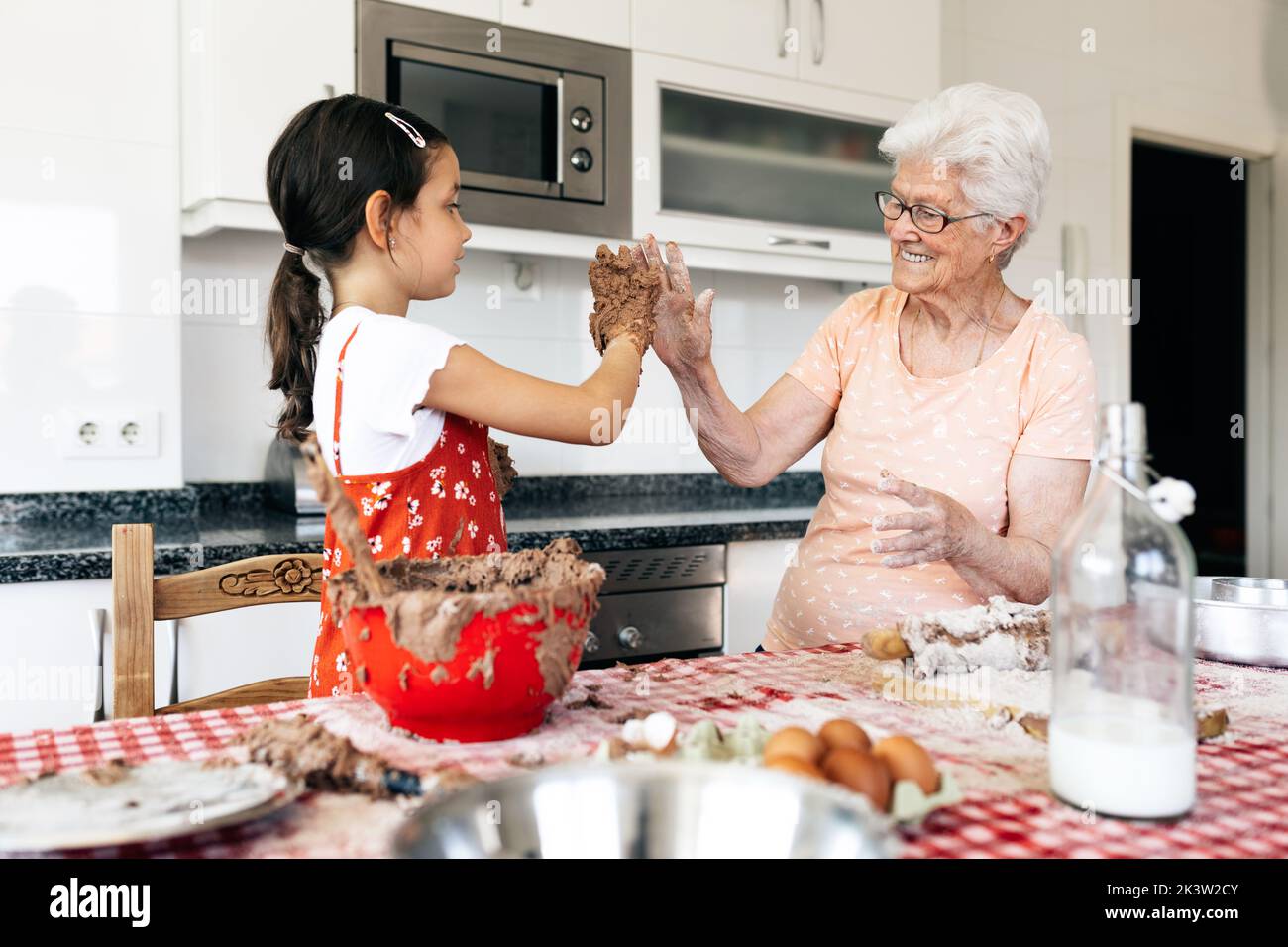 Nonna allegra con nonna che si diverte mentre si guarda a tavola con pasta di torta in casa Foto Stock