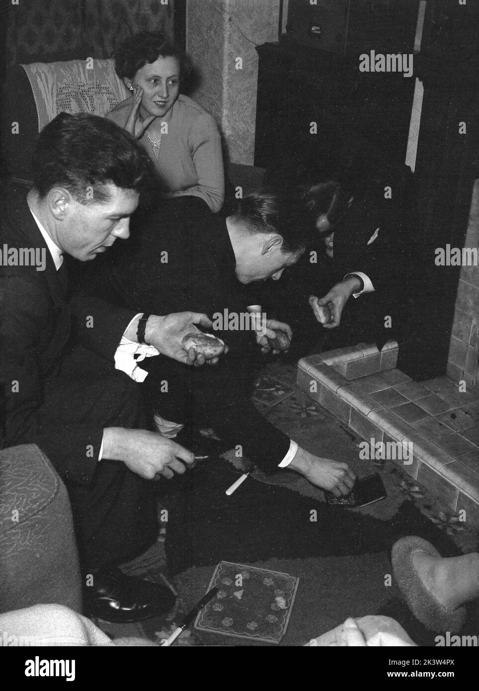 1956, storico, famiglia nella sala d'ingresso, due giovani uomini che mangiano panini davanti all'incendio, Inghilterra, Regno Unito. Foto Stock