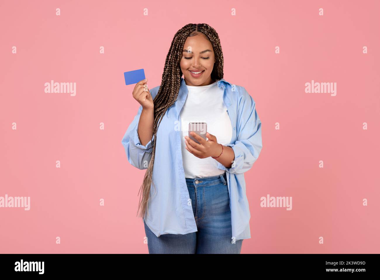 African Woman Shopping con carta di credito e cellulare, sfondo rosa Foto Stock