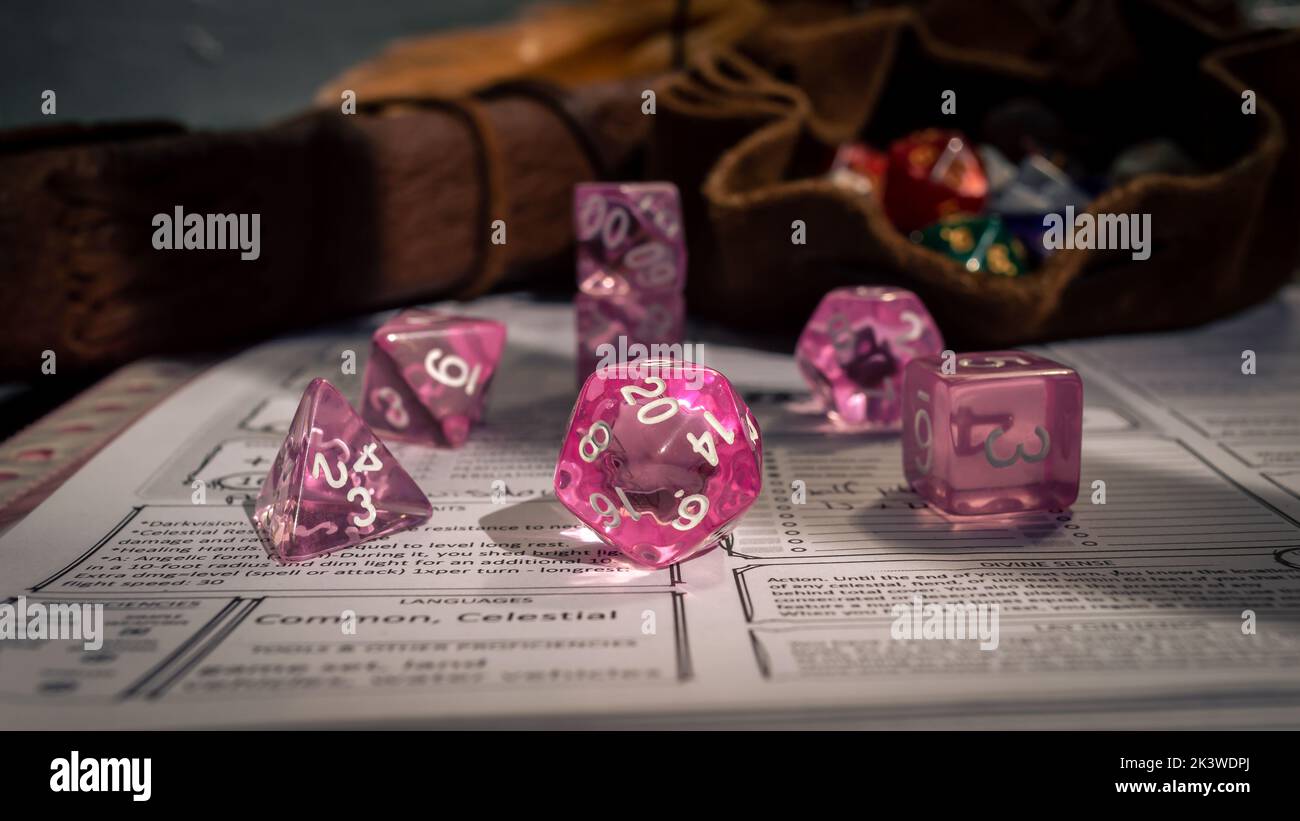 Immagine di un set di dadi RPG rosa trasparenti su un foglio di un personaggio Foto Stock