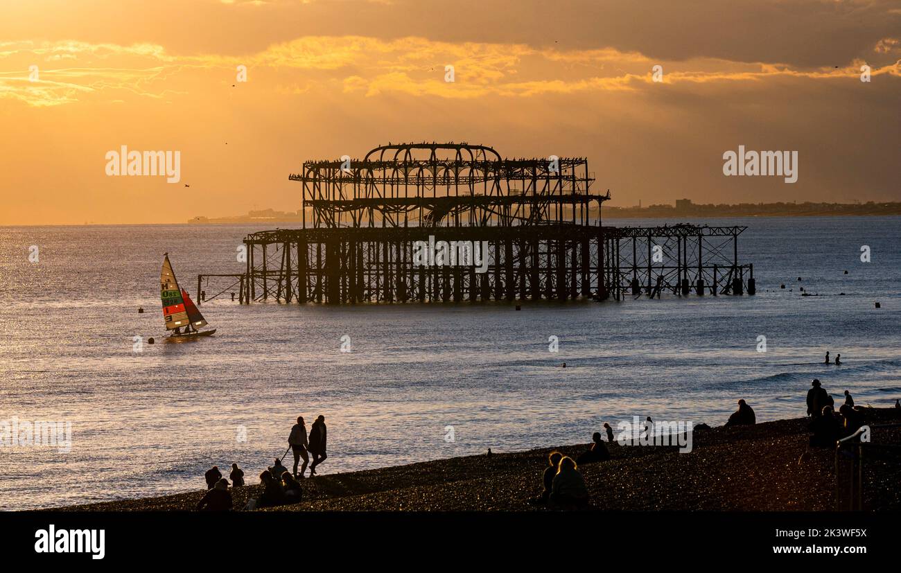 Brighton UK 28th settembre 2022 - i visitatori guardano il tramonto sul West Pier sul lungomare di Brighton dopo una bella giornata autunnale lungo la South Coast . Tuttavia il tempo umido e ventoso è previsto per arrivare il Venerdì nel Regno Unito . : Credit Simon Dack / Alamy Live News Foto Stock