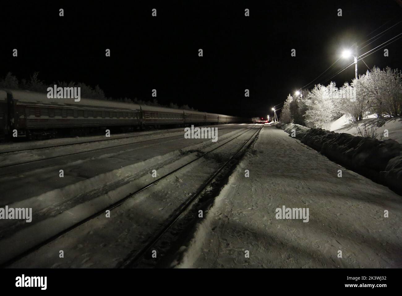 Vista sui binari ferroviari e sui vagoni ferroviari alla stazione Pyayve sul servizio ferroviario passeggeri più a nord del mondo tra Murmansk e Nikel nella notte polare Foto Stock