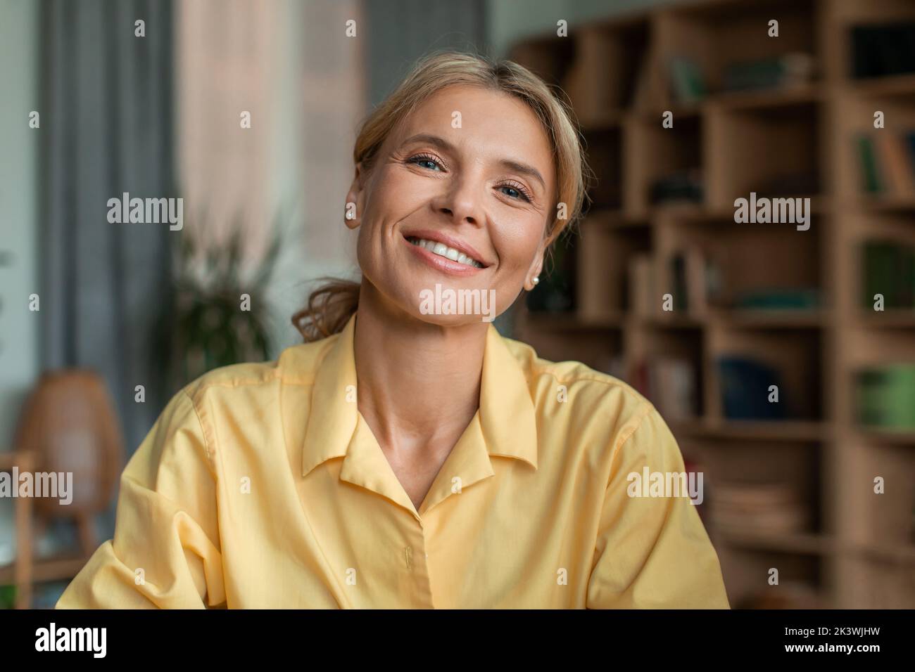 Ritratto di psicologa femminile di mezza età positiva che parla con la fotocamera e sorride durante la sessione di terapia in ufficio Foto Stock