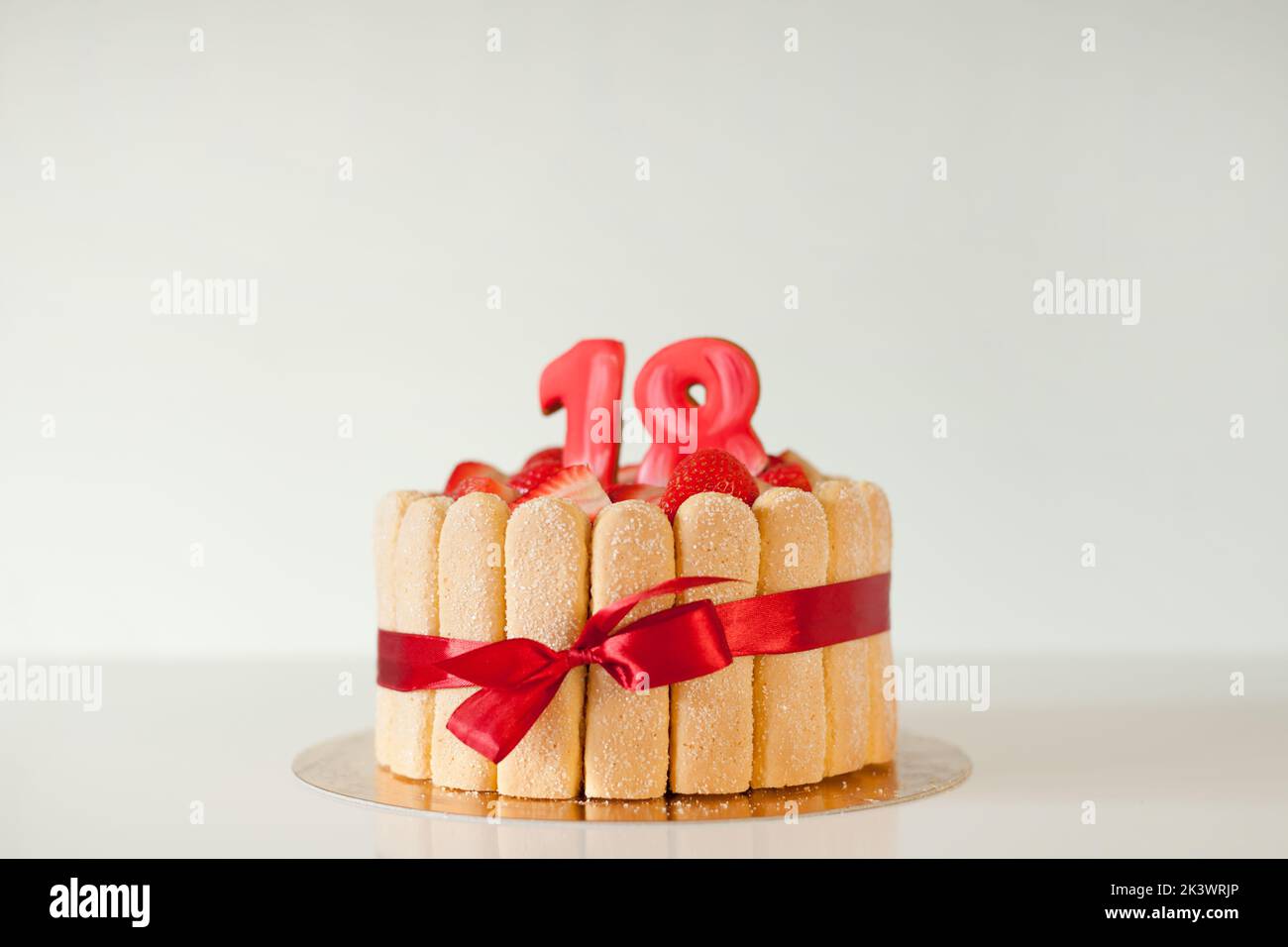 Torta deliziosa con numeri su sfondo grigio, spazio per il testo. Festa di arrivo - 18th compleanno. Foto Stock