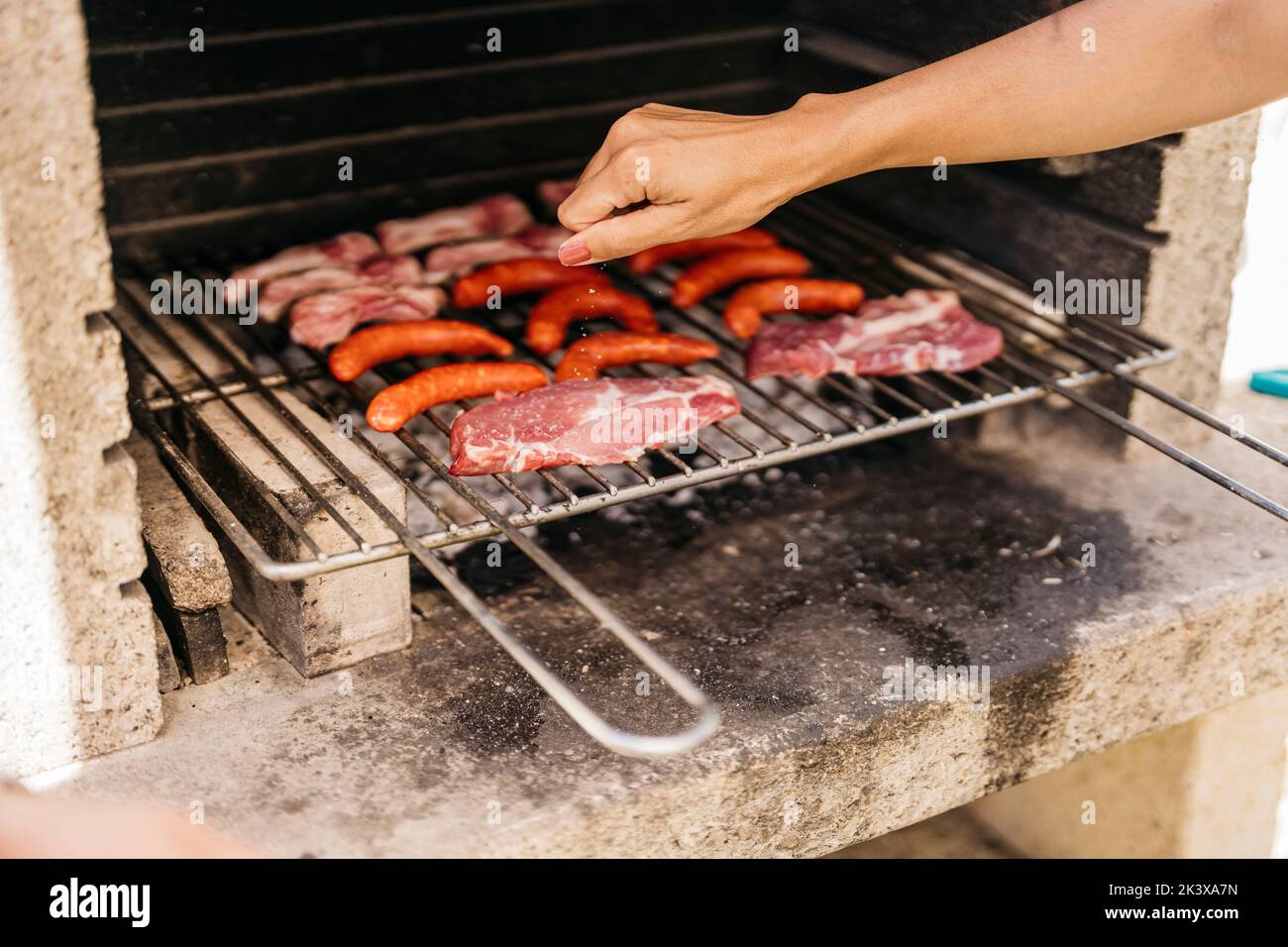 mani di giovane donna latina strofinare il sale sulla carne al barbecue Foto Stock