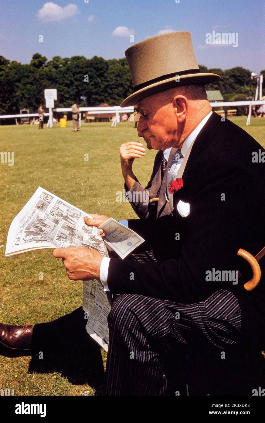 Uomo in formale Attrire leggendo giornale, mentre frequentano English Derby, Epsom Downs Racecourse, Epsom, Surrey, Inghilterra, UK, toni Frissell Collection, 3 giugno 1959 Foto Stock