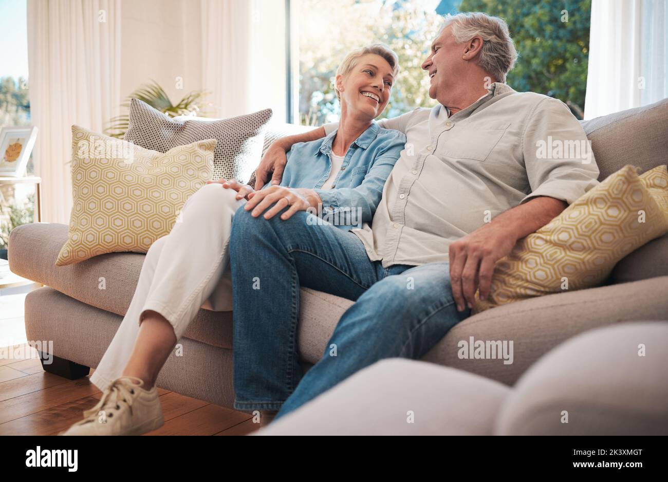 La coppia di pensione sorride sul divano che parla di matrimonio felice, pensione e ricchezza in casa o casa di vacanza. Abbraccia, ama e cura la donna anziana con l'uomo Foto Stock