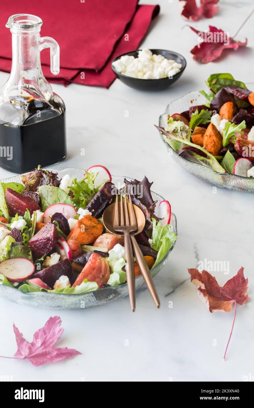 Ciotole di insalata di barbabietole e carote arrosto servite con feta e condimento balsamico. Foto Stock