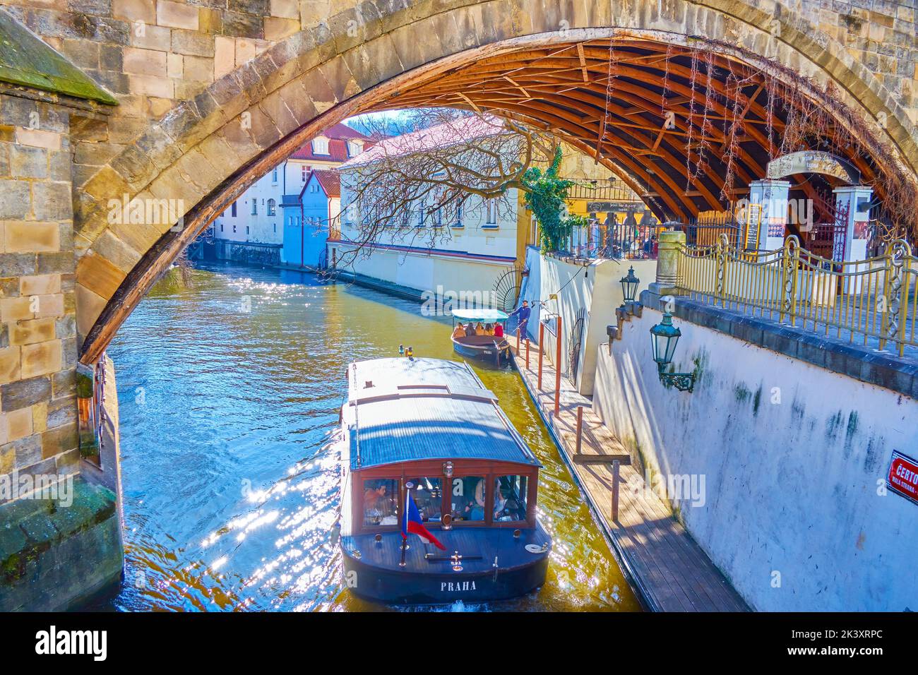 Una piccola barca turistica naviga sotto il Ponte Carlo nel quartiere di Mala Strana a Praga, Repubblica Ceca Foto Stock