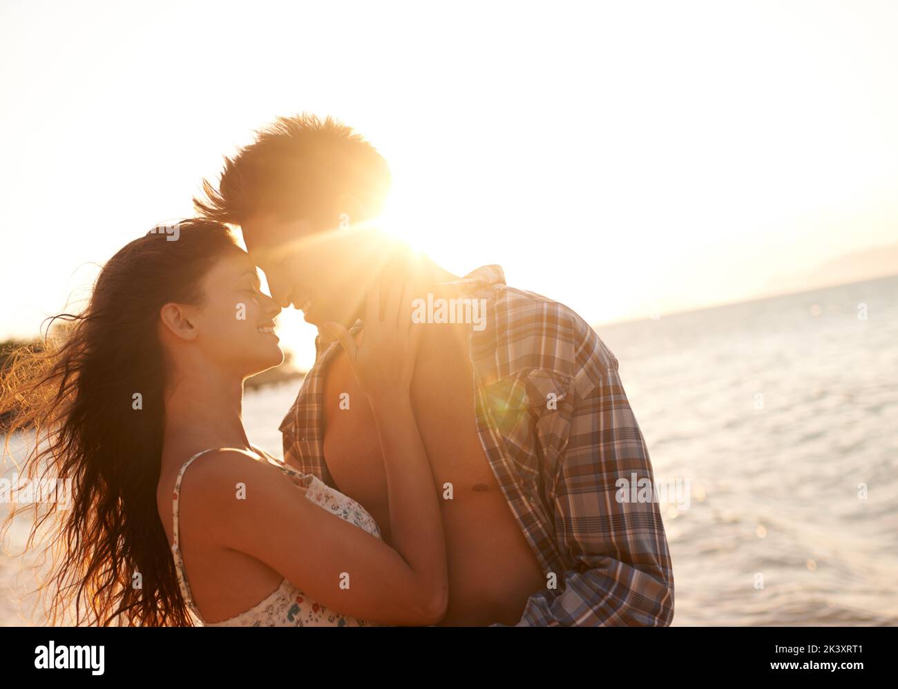 Bacia al tramonto, una giovane coppia che si gode una vacanza in spiaggia. Foto Stock