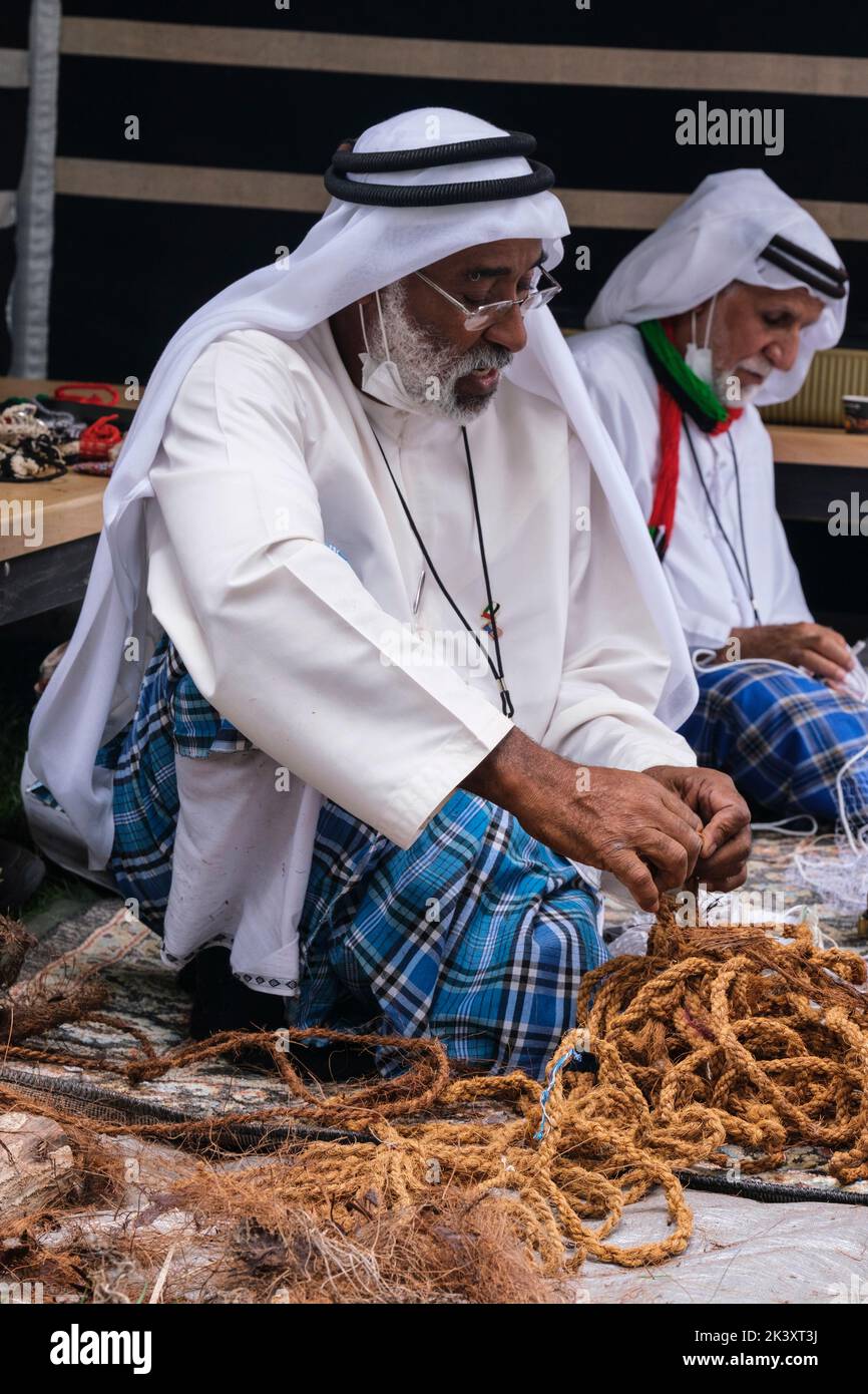 Afro-Arab da Abu Dhabi al Folklife Festival di Dishdasa, Ghutra, e AGAL, facendo corda di fibra di cocco per l'uso nella realizzazione di reti da pesca tradizionali. Foto Stock