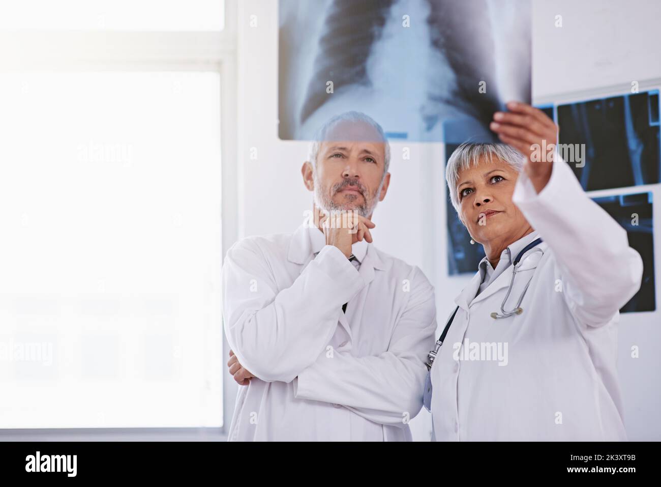 Tenere d'occhio eventuali irregolarità. Due medici che osservano una radiografia insieme. Foto Stock