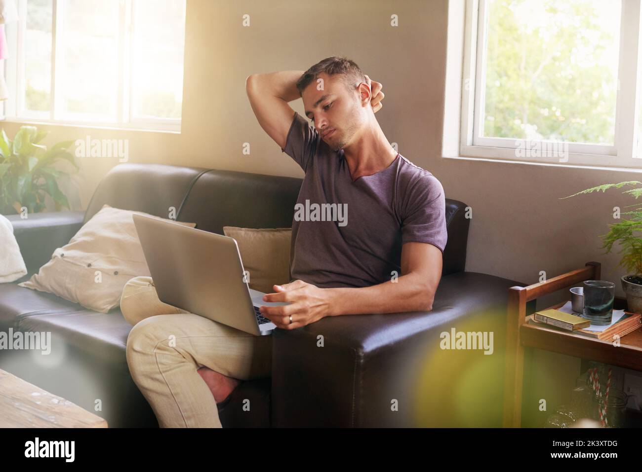 Ci si rilassa con il computer portatile. Un bel giovane che usa un computer portatile sul divano di casa. Foto Stock