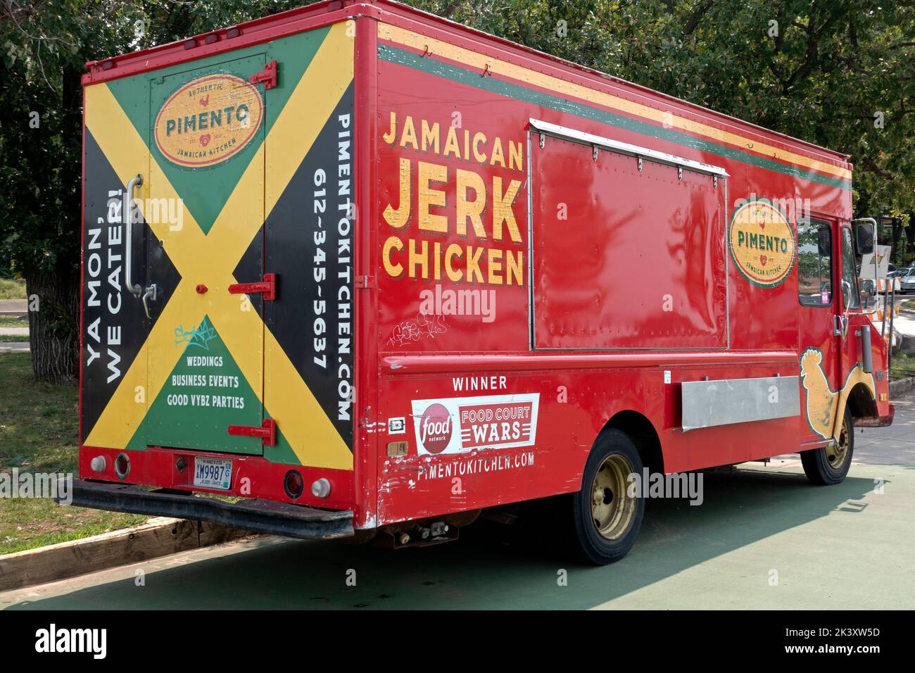 Camion colorato cibo rosso che serve Jamaican Jerk Chicken vicino al lago BDE Maka Ska. Minneapolis, Minnesota, Minnesota, USA Foto Stock