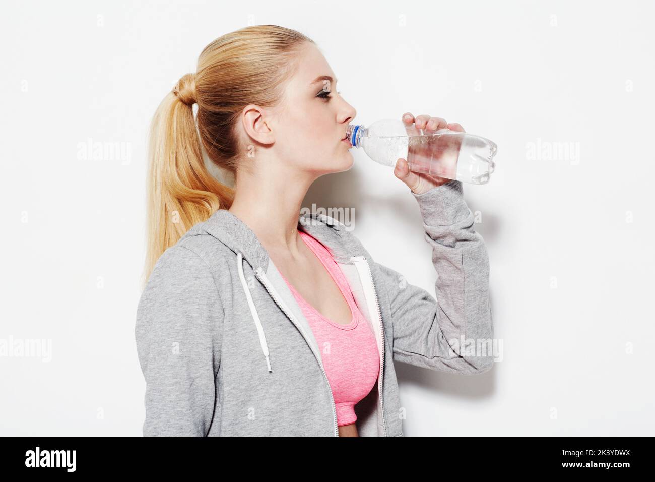 Mantenere idratato. Studio shot di una giovane donna in abbigliamento da ginnastica bere da una bottiglia d'acqua. Foto Stock