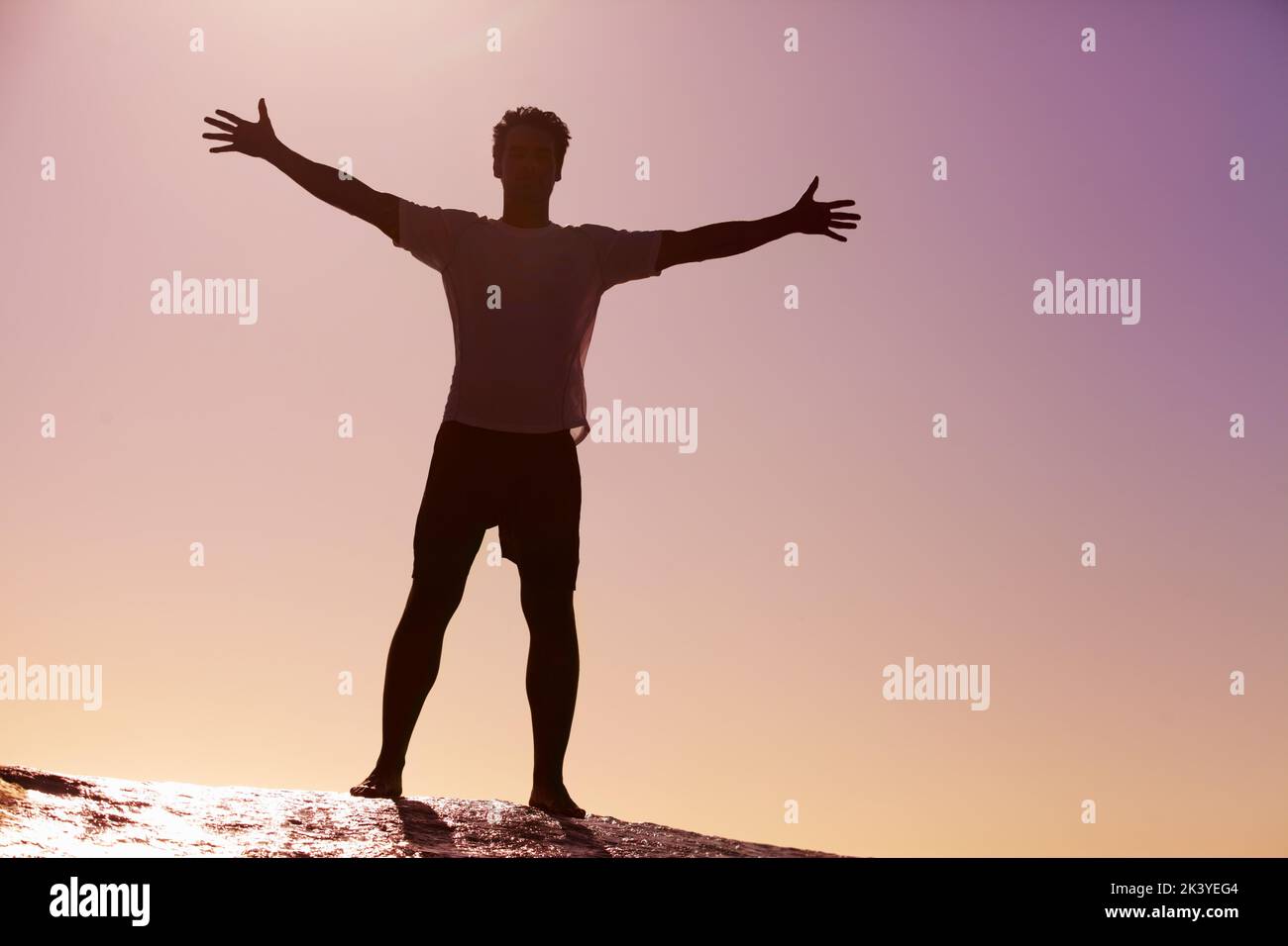 In cima al mondo. Silhouette ripresa da un giovane uomo in piedi contro il cielo. Foto Stock