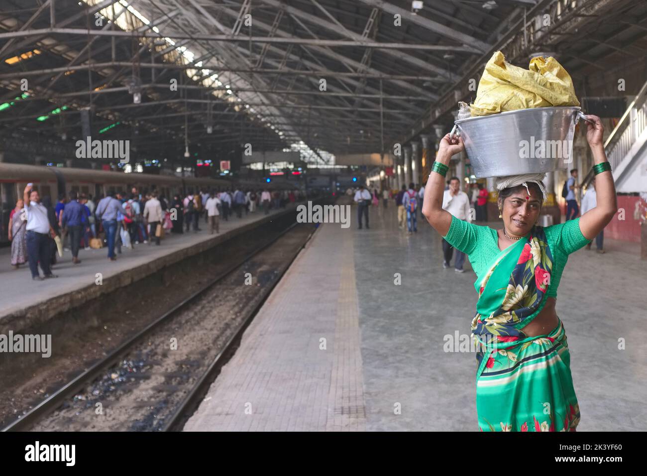 Una donna indiana al Chhatrapati Shivaji Maharaj Terminus (CSMT) a Mumbai, India, che porta un secchio di pesci sulla testa per avanzare con il treno locale Foto Stock