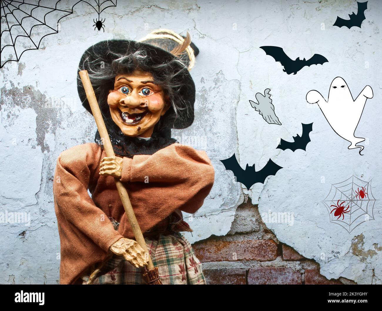 Strega di Halloween in vestito decorato che tiene una scopa di legno. Trucco o trattare. Halloween felice. Foto Stock
