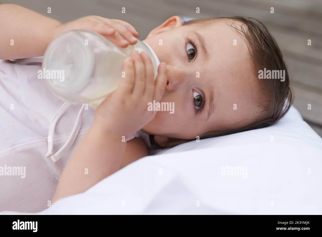 Tempo di allattamento per il bambino. Una bambina sdraiata mentre beve la formula da una bottiglia. Foto Stock