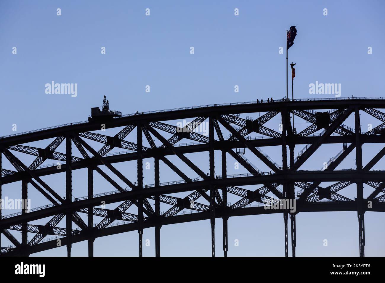 Parte del Sydney Harbour Bridge, Sydney, Australia, che si staglia contro un cielo crepuscolo. Una festa di arrampicatori di ponte si trova vicino ai flagpoles Foto Stock