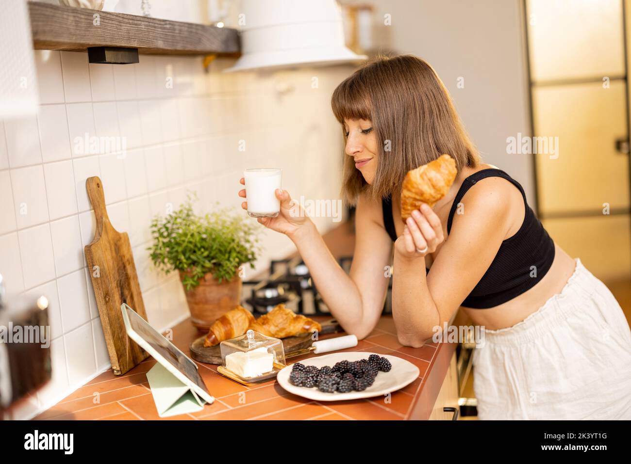 Donna che fa colazione in cucina a casa Foto Stock