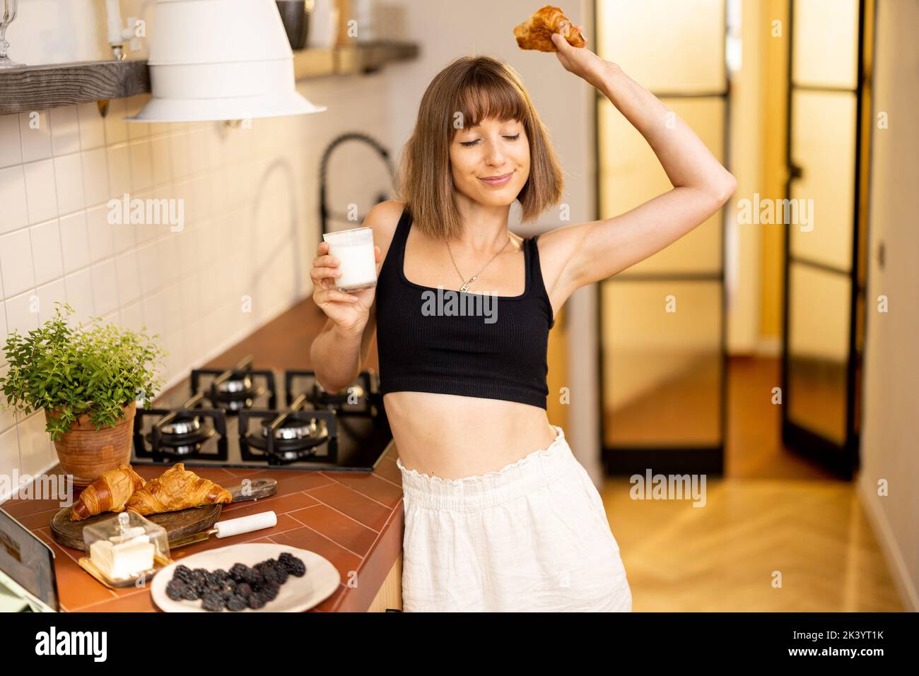 Donna che si allunga durante una colazione in cucina Foto Stock