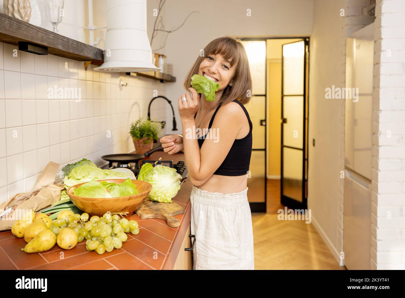 La giovane donna cucina sano cibo vegetariano in cucina a casa Foto Stock
