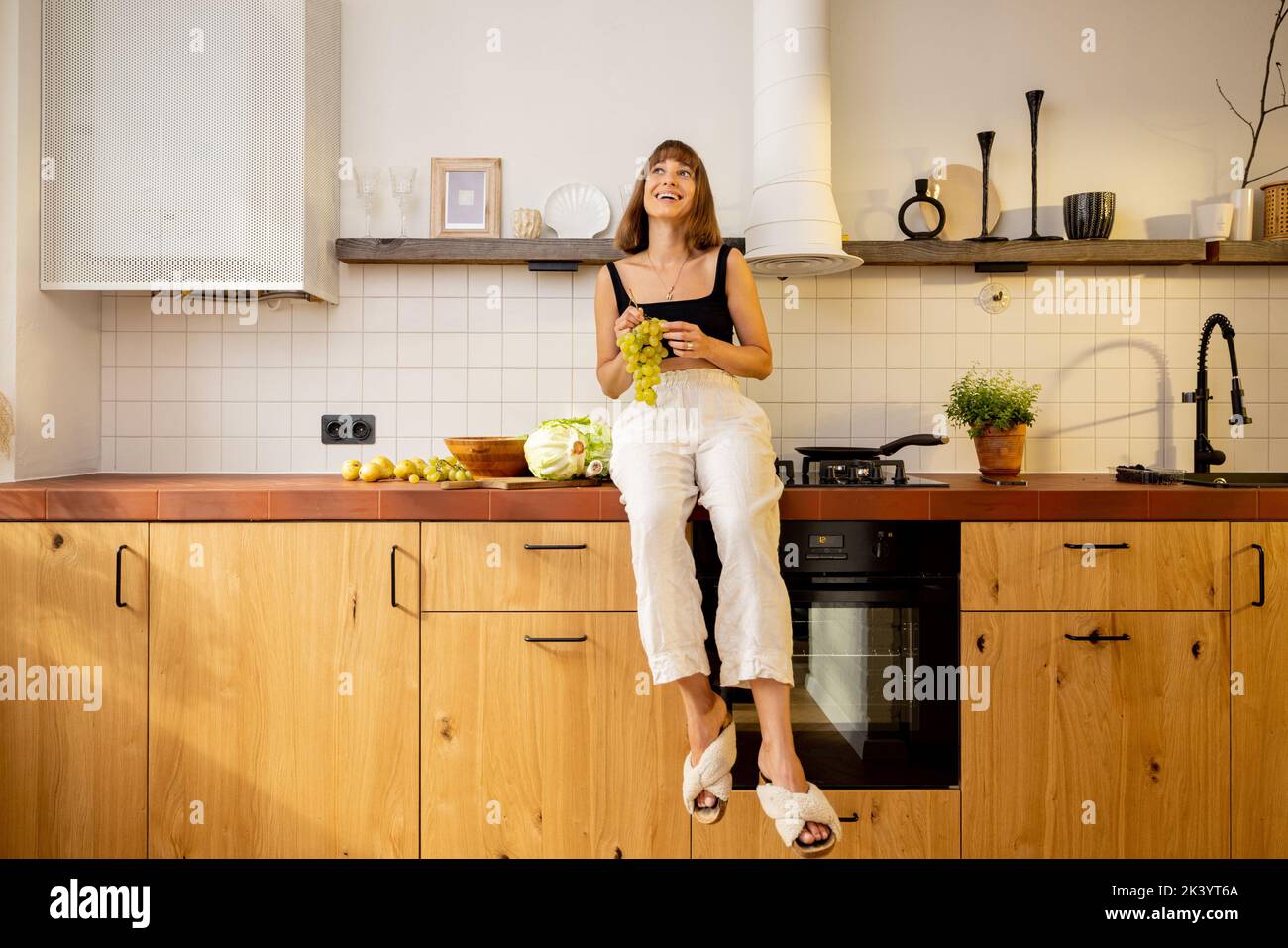 Donna si siede su un tavolo da cucina con cibo sano a casa Foto Stock