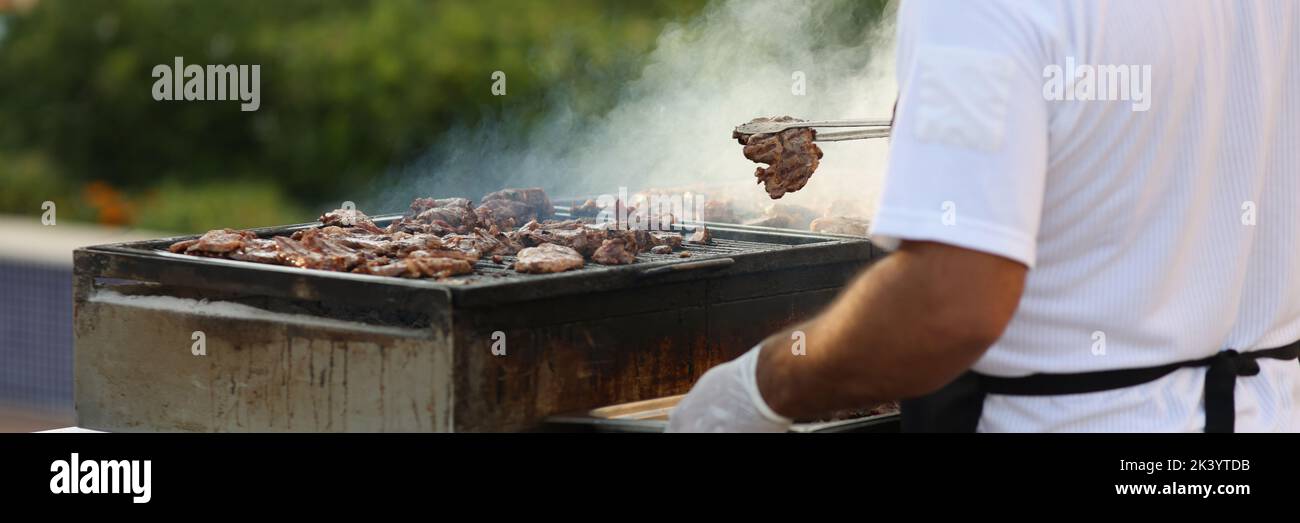 Costruzione in metallo per friggere la carne in natura, maschio chef fare grill Foto Stock