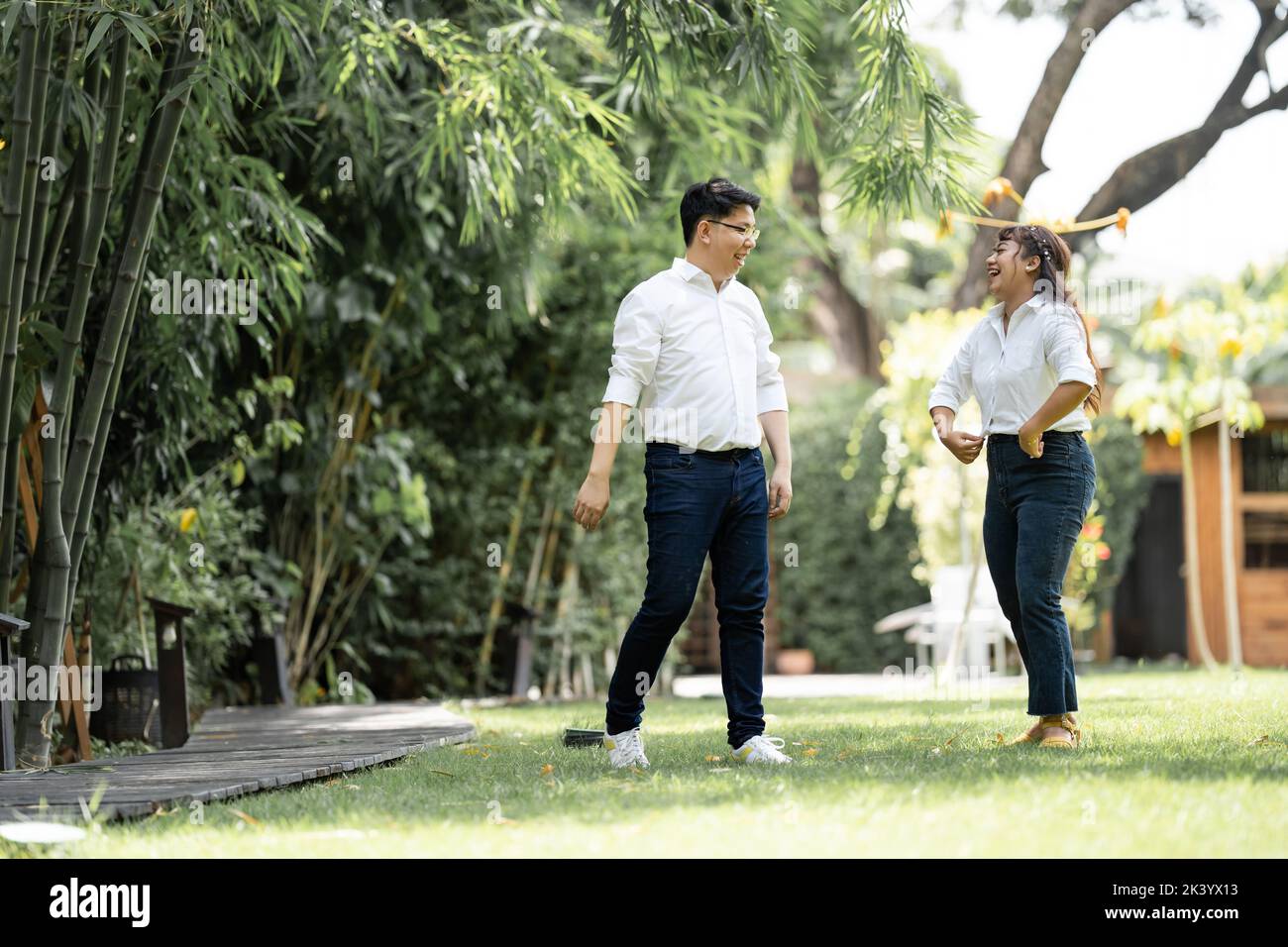 Asian uomo e donna scattando una foto di pre-matrimonio con la donna che afferra la sua spalla e rinforzando l'uomo nel giardino. Foto Stock