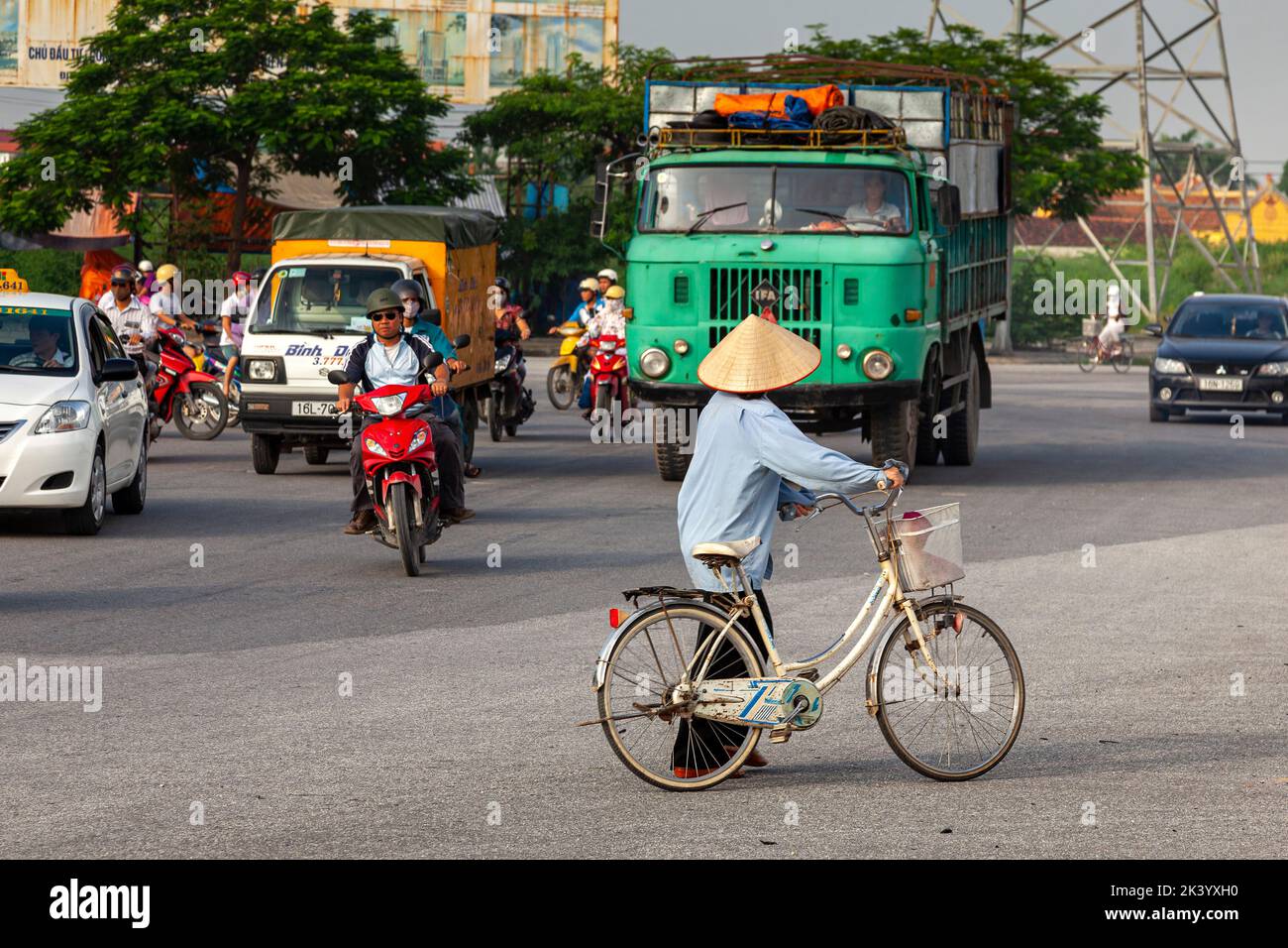 Signora vietnamita che indossa un cappello conico di bambù, con bicicletta, Hai Phong, Vietnam Foto Stock