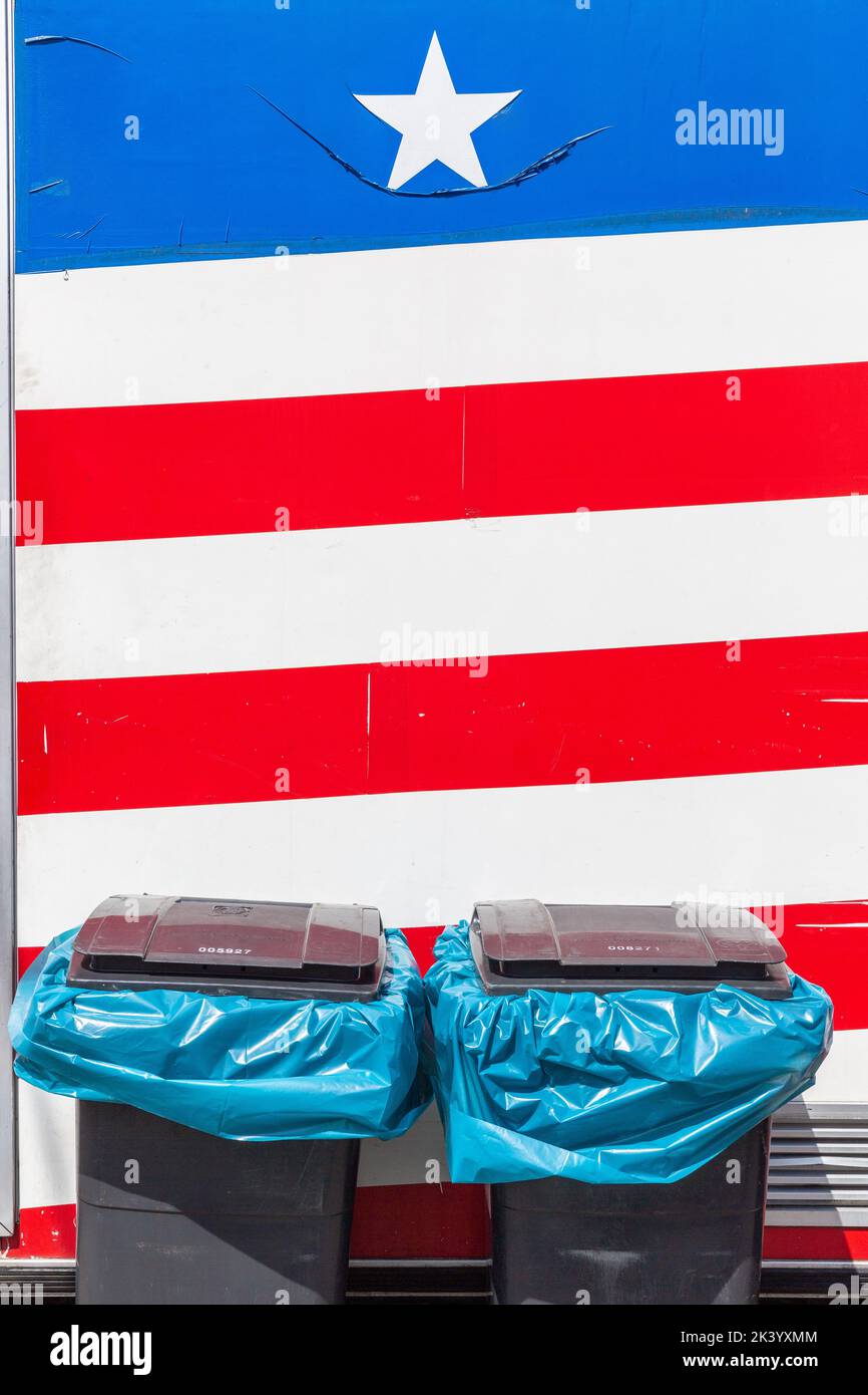 Due bidoni di rifiuti in piedi guardia ai piedi di una bandiera degli Stati Uniti Foto Stock