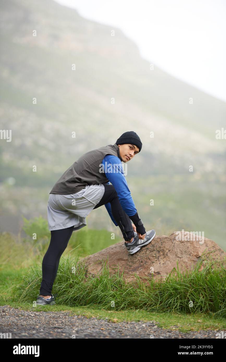 Godendo di una corsa mattutina. Un giovane uomo che legava la sua scarpa lacci prima di una corsa mattutina in inverno. Foto Stock