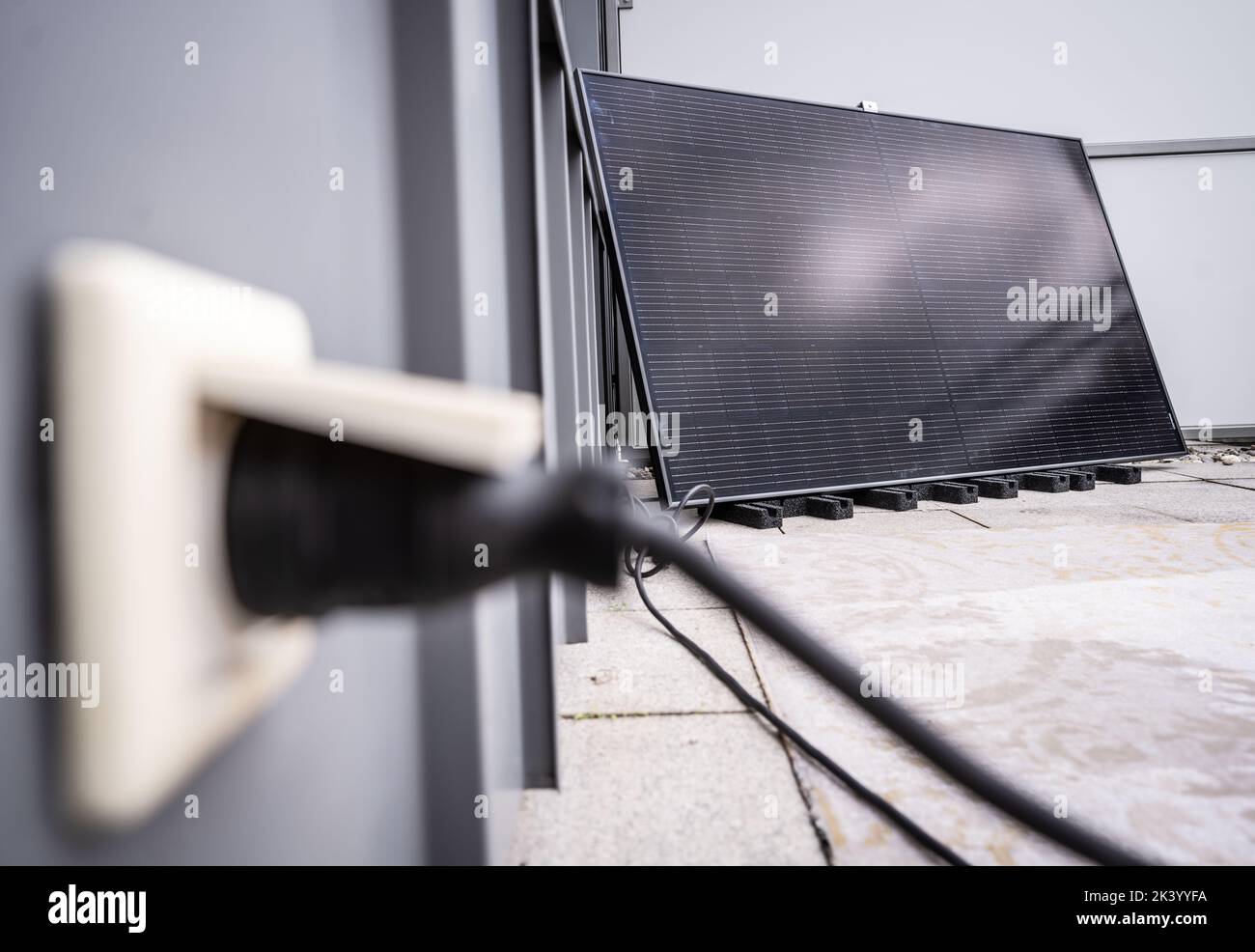 28 settembre 2022, Hesse, Francoforte sul meno: Il raddrizzatore necessario per alimentare l'elettricità nella rete domestica è raffigurato di fronte ad un modulo solare per una cosiddetta centrale elettrica a balconata, che si trova su un balcone a Francoforte. Con l'ausilio di un raddrizzatore, l'elettricità può essere alimentata direttamente nella presa domestica. Foto: Frank Rumpenhorst/dpa Foto Stock