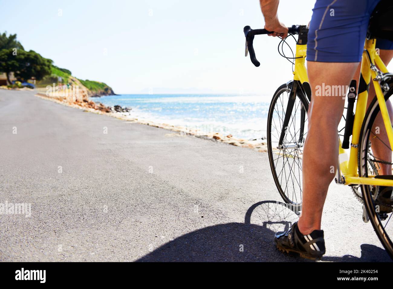 Godendo il paesaggio mentre si esercita. Vista ritagliata di un ciclista che pedeggia lungo una strada oceanica. Foto Stock