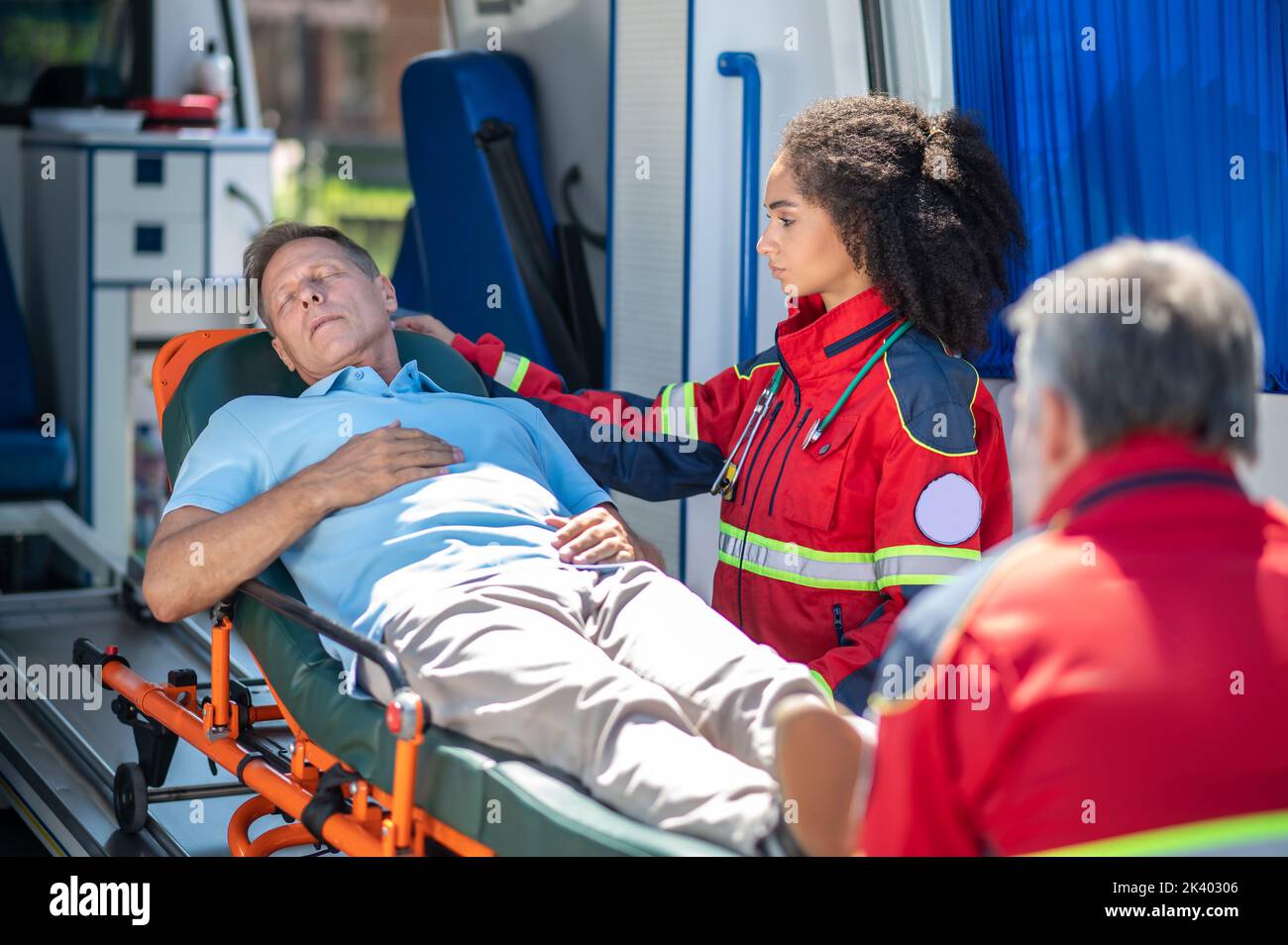 Personale paramedico che trasporta un uomo inconscio alla vettura dell'ambulanza Foto Stock